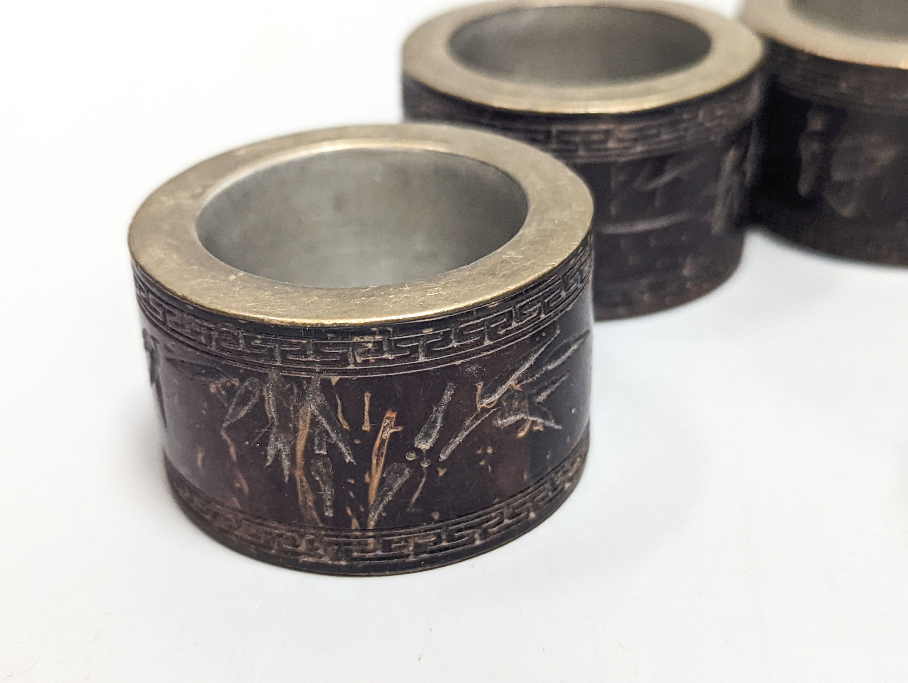 A Chinese ivory concentric puzzle ball, 6 Chinese coconut and brass mounted napkin rings.